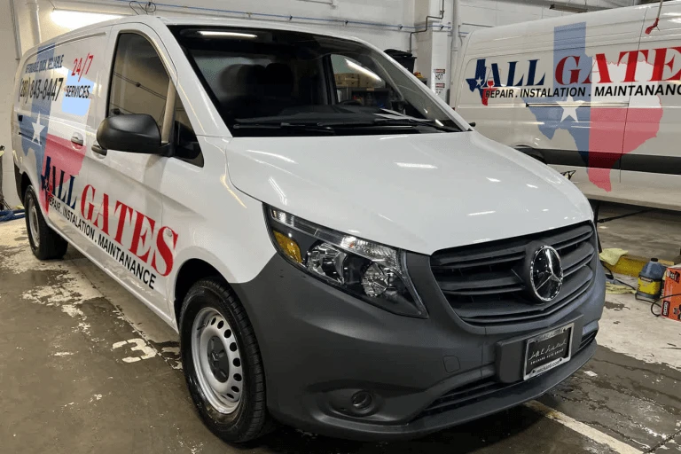 A white utility van with the branding "ALL GATES: Repair, Installation, Maintenance" on its side parked in a garage. The van has a Mercedes-Benz logo on the front and offers services like driveway gate repair. Another similar van is partially visible in the background.